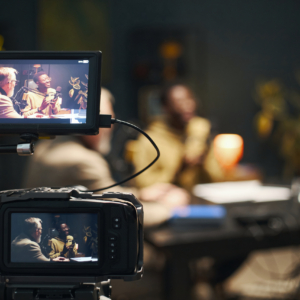 People Recording Podcast On Camera People sitting at table and recording online podcast on professional camera