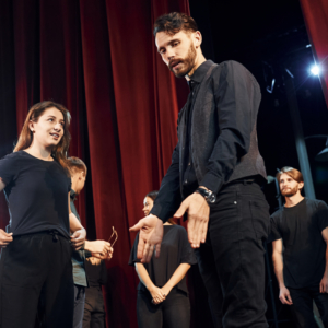 Two people talking. Group of actors in dark colored clothes on rehearsal in the theater Two people talking. Group of actors in dark colored clothes on rehearsal in the theater.